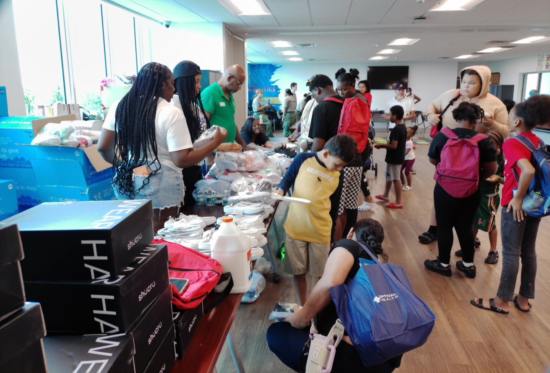 Families and volunteers selecting school supplies at a community event